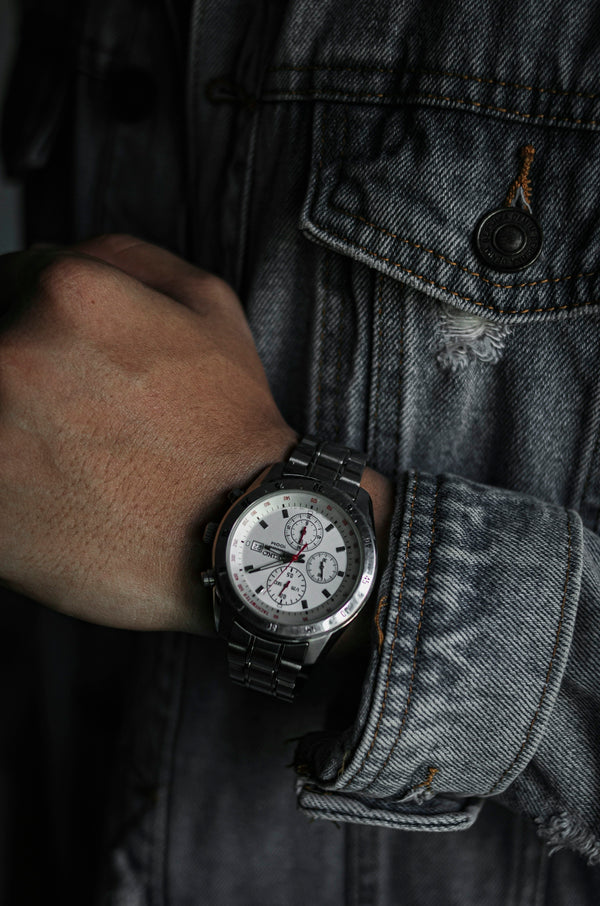 person wearing silver link bracelet round analog watch