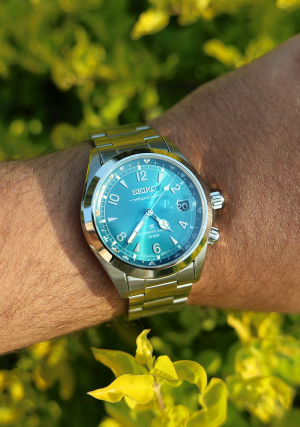 Seiko watch on a wrist with green foliage background.